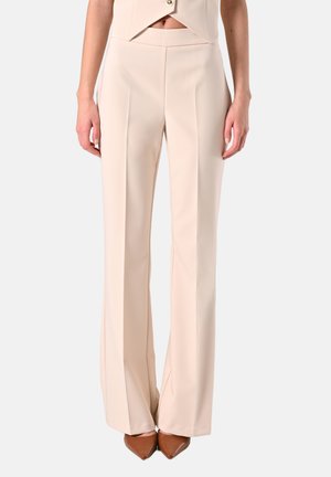 Pantaloni beige a gamba larga realizzati in tessuto liscio, caratterizzati da pieghe frontali nette. Abbinati a décolleté marroni con punta per un look elegante.