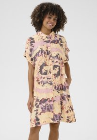Kortärmad skjortklänning i en tie-dye-mönster av gula, rosa och lila nyanser. Tillverkad av lätt tyg, med avslappnad passform och fickor.
