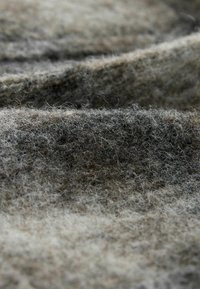 Graues und braunes Filzgewebe mit einer weichen, texturierten Oberfläche, die miteinander verflochtene Fasern und ein leicht marmoriertes Muster in natürlichen Farbtönen zeigt.