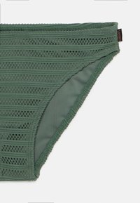 Parte inferiore di bikini verde realizzata in tessuto testurizzato con righe orizzontali e bordo scallop. Presenta una fodera interna liscia e cuciture laterali.