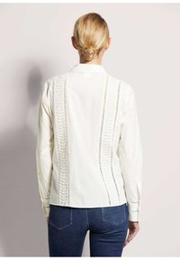Witte blouse met lange mouwen en delicate uitsnijdingen langs de rug en mouwen, gestructureerde kraag en een los zittende pasvorm.