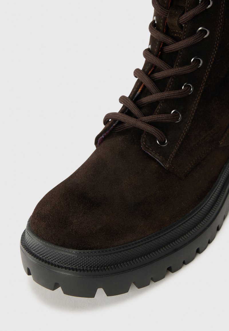 Braune Wildlederstiefel mit runder Zehenpartie, schwarzer Gummisohle und braunen Schnürsenkeln. Verfügt über eine strukturierte Oberfläche und verstärkte Ösen.