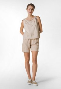 Beige letní top z lnu s volným výstřihem a ramenními šňůrkami, spárovaný s odpovídajícími šortkami s uvolněným střihem a ohrnutými manžetami.