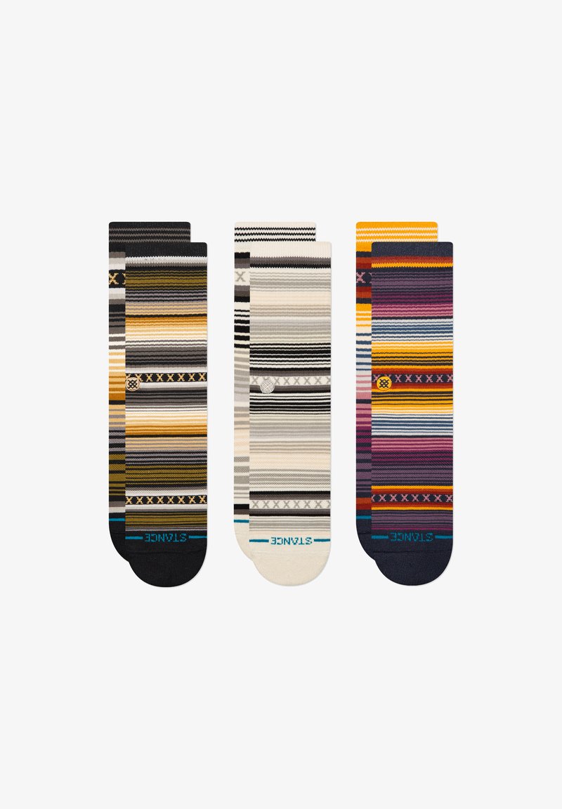 Tres pares de calcetines estampados con rayas en varios colores, incluyendo amarillo, gris, negro y púrpura. Cada calcetín tiene un diseño y textura únicos.