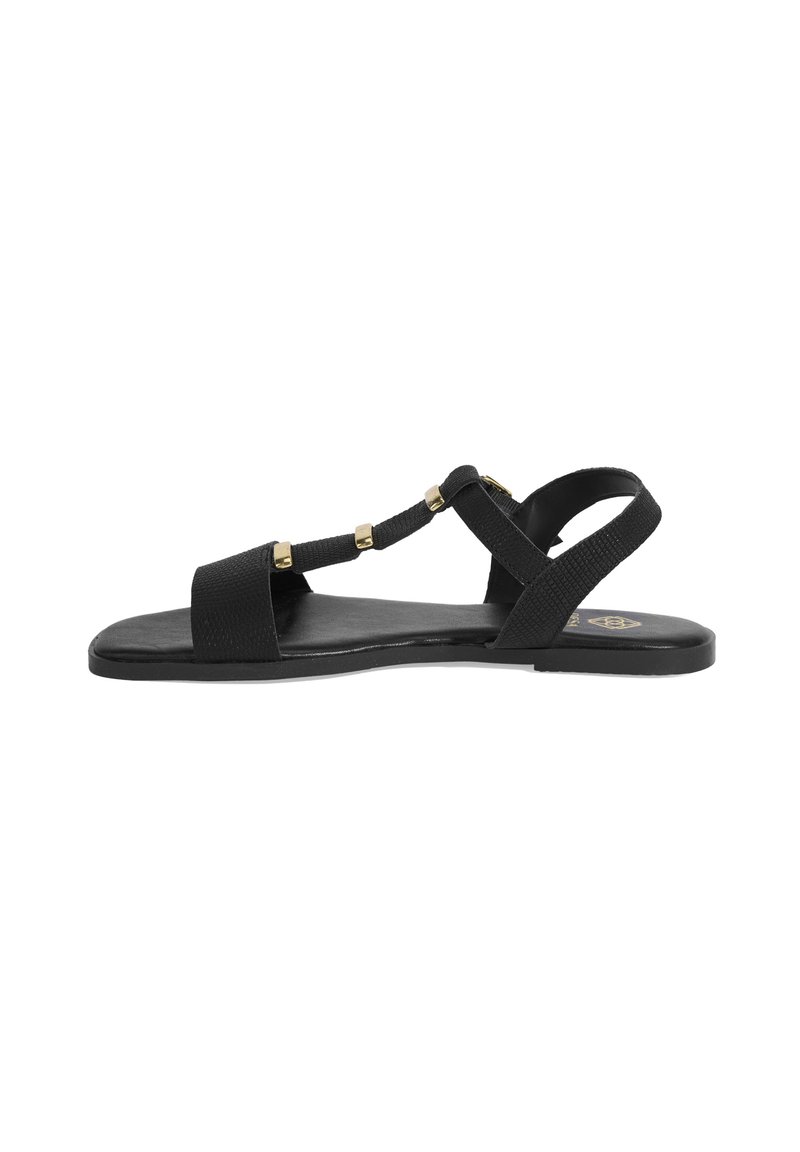 Black flat sandals featuring a textured strap design, gold accents, and a minimalist shape with an open toe. Rubber sole for comfort.