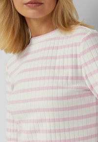 Striped long-sleeve top in white and soft pink, featuring a ribbed texture and a round neckline. Subtle horizontal stripes throughout.
