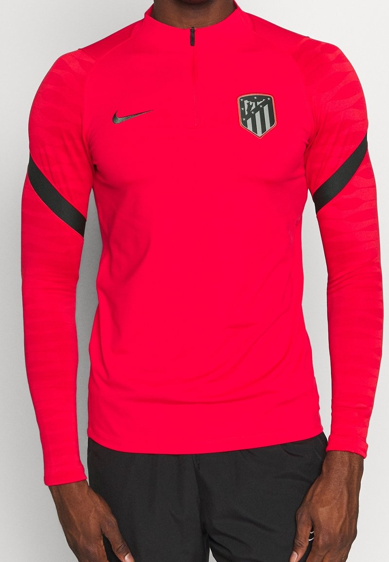 Nike athletic top in bright pink with long sleeves and a half-zip neckline. Features black accent stripes and a team logo on the chest.
