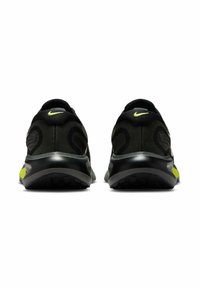 Czarne buty sportowe z teksturowaną górą, żywe zielone akcenty i zaokrąglony design obcasa. Logo Nike na pasku na pięcie.
