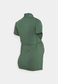Zielona sukienka w stylu polo, z krótkimi rękawami i dopasowanym krojem. Wykonana z miękkiego materiału o delikatnym połysku; ma wiązany pasek w talii dla lepszego kształtu.