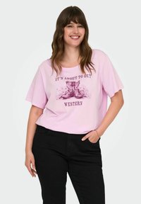 Light pink cotton t-shirt with short sleeves featuring a western graphic design in darker pink, paired with black pants.