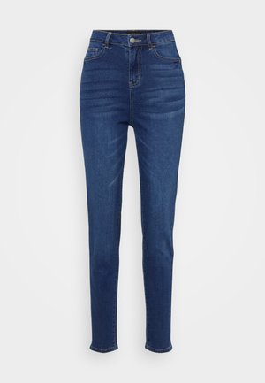 Høyt liv, slim-fit jeans i mørkeblå denim. Har fem lommer, belteseler og knappelukking med subtil falming langs bena.