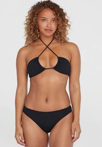 Juodas bikinis, kuriame yra trikampio formos viršus su surinkta medžiaga ir susikertančiomis petnešėlėmis, derinamas su atitinkančiomis žemo liemens kelnaitėmis. Lygus tekstūra.