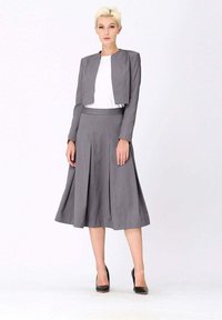 Veste grise cintrée au design court, associée à une jupe plissée assortie. L'ensemble présente une texture lisse et une silhouette épurée.