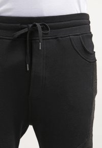 Svarta sweatpants med dragsko i midjan, med sidfickor och strukturerade detaljer på ytterseam. Tillverkade av ett mjukt tyg.