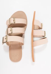 Sandali rosa chiaro con tre cinturini testurizzati e fibbie dorate. Suola piatta con una base beige e un branding sottile sulla soletta.