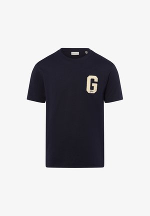 Námořnická modrá bavlněná tričko s velkou smetanovou nášivkou "G" na levé straně hrudi, krátkými rukávy a kulatým výstřihem. Jednoduchý a moderní design.