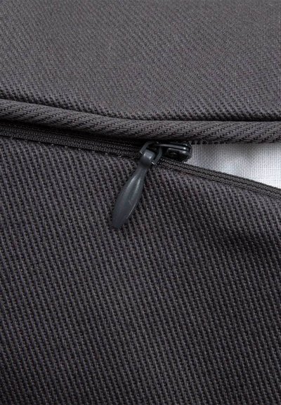 Κοντινό πλάνο ενός μερικώς ξεκουμπωμένου μαύρου φερμουάρ από ύφασμα με υφή και ορατό μοχλό φερμουάρ.