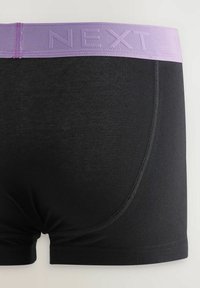 Fekete boxer alsónadrág lila elasztikus derékpánttal, amelyen dombornyomott "NEXT" felirat található. Simaság jellemzi, közel illeszkedő dizájnnal és lapos varrásokkal.