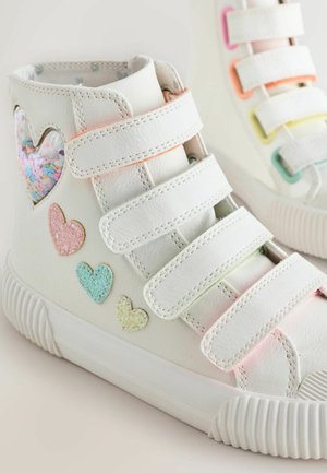 Weiße High-Top-Schuhe mit Klettverschlüssen, mit einem transparenten herzförmigen Ausschnitt, der mit Glitzer gefüllt ist, und mehrfarbigen Herz-Applikationen.