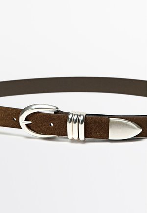 Bruine suède riem met een zilveren metalen gesp, drie decoratieve zilveren ringen en een puntig einde voor sluiting. Detail van de gestructureerde oppervlakte zichtbaar.