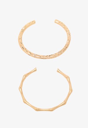 Twee goudkleurige ringen: de ene met een gestructureerd oppervlak en een gedraaide vorm, de andere die lijkt op bamboe met gladde, ronde secties.