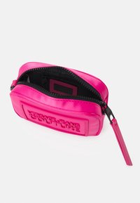 Rosa, texturerad dragkedjepåse med präglad "Versace Jeans Couture"-logotyp. Har en slät yta och svart innervägg.