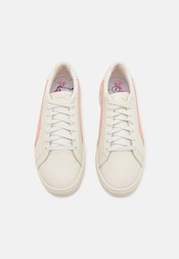 Białe skórzane sneakersy z różowymi akcentami po bokach, płaskimi sznurowadłami i kolorowym wnętrzem z kwiatowym wzorem. Gładka faktura przez cały czas.