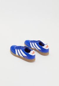 Blå lærredssneakers med hvide striber, gummirublersål og røde accenter. Har polstret krave og snørebåndsdesign.
