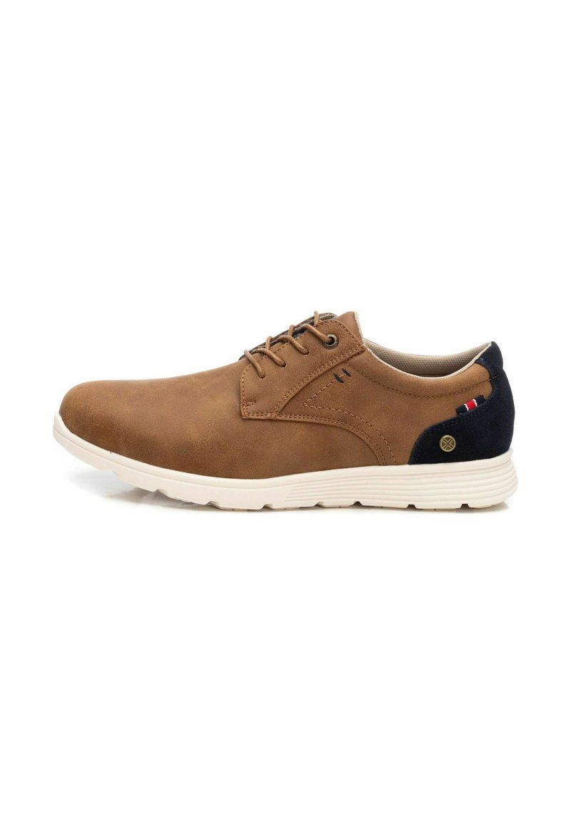 Zapato de cuero marrón con cordones y acabado liso, suela blanca y acento en el tacón azul marino con un pequeño logo y detalles en rojo, blanco y azul.