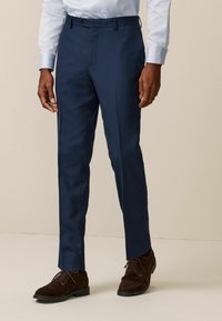 Pantalones azul marino ajustados, fabricados en un tejido suave con frente plano, que cuentan con un cierre de un solo botón y bolsillos frontales.