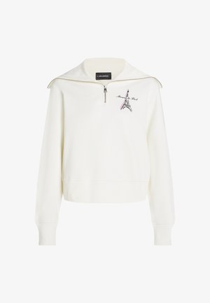Sudadera blanca con cuello de media cremallera, que presenta un gráfico de la Torre Eiffel y texto. Textura suave, corte relajado y puños acanalados.