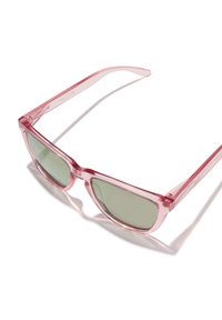 Roza prozorna sončna očala z zelenimi lečami, kotno obliko in tankimi kraki. Imajo minimalno blagovno znamko na stranicah.