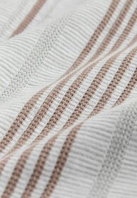 Bomuldsstof med teksturerede hvide og bløde brune striber, med et subtilt vævet mønster og glat tekstur, arrangeret i bølger.