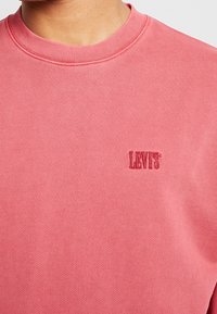 Sweatshirt rose de Levi's avec col rond, détail à côtes et petit logo brodé Levi's de couleur assortie. Texture lisse.