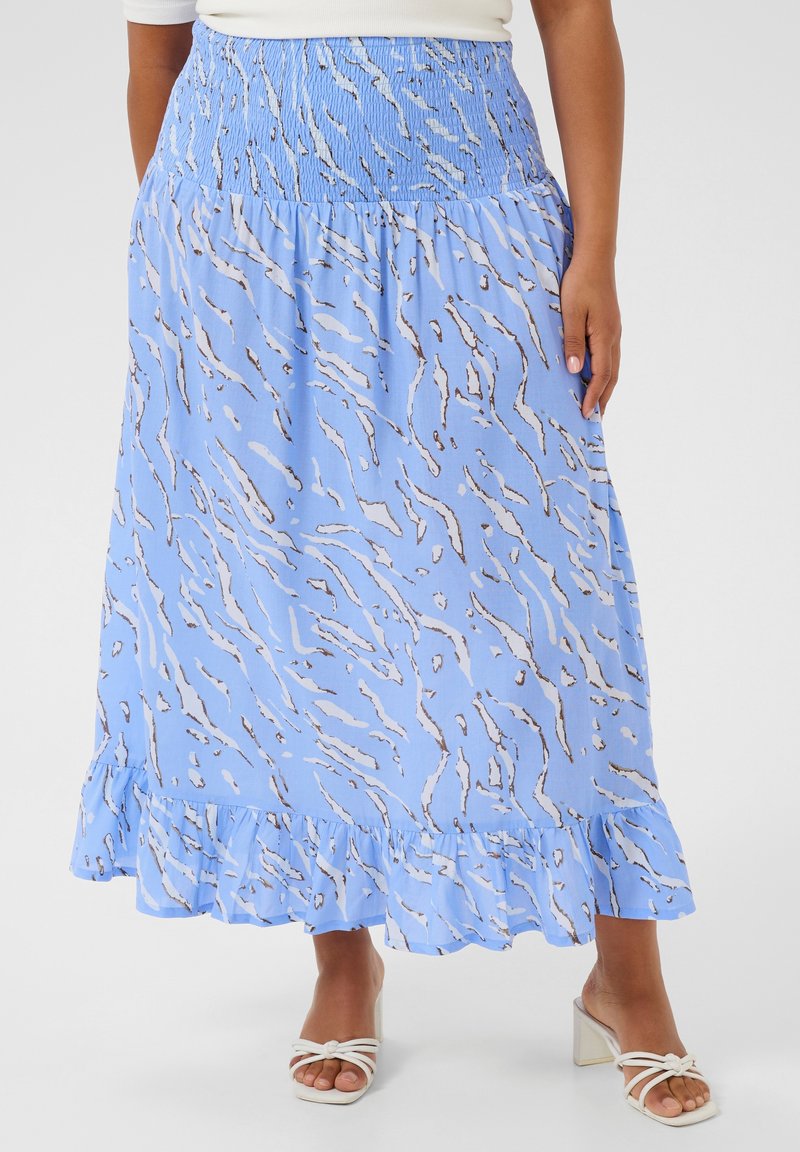 Lichtblauwe rok met een golvend bruin patroon, voorzien van een smocktail en een gerimpelde zoom. Gecombineerd met witte hakken sandalen.