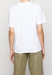 Hvid bomulds T-shirt med korte ærmer, rund hals og afslappet pasform. Set fra ryggen, der fremviser en glat tekstur og syningsdetaljer.
