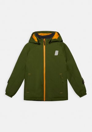 Chaqueta verde con capucha, cremallera naranja, capucha con forro naranja, dos bolsillos delanteros y un pequeño parche blanco en el pecho.