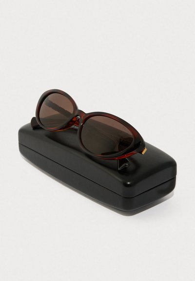 Ochelari de soare cu nuanță de brun, cu rame ovale, având un model întunecat de țestoasă. Însoțiți de un toc protector elegant, de culoare neagră.