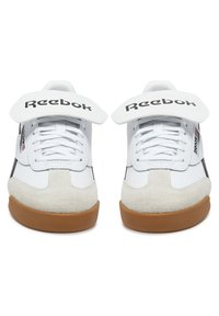 Baltie balti ādas sporta apavi ar zamšādas purngalu, melniem akcentiem un Reebok logo. Iespējas: šņores un liels velcro siksna aizdarei.