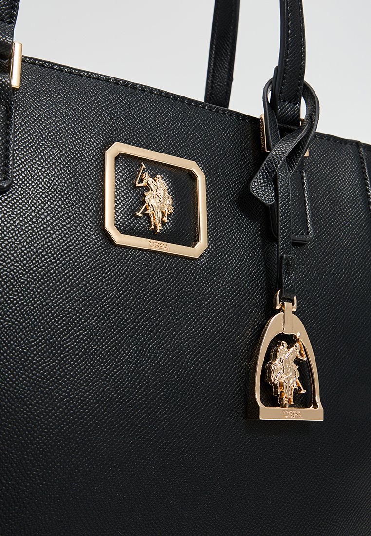 Bolso de cuero negro texturizado con una placa de metal dorado con el logo y una etiqueta decorativa con un motivo de jinete.