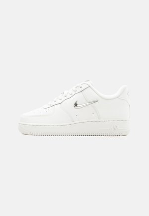 Hvid Nike Air Force 1 sneaker med metallisk sølv swoosh-logo, snørelukning foran, gennemhullet tå og tekstureret gummisål.