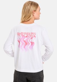 Weißes Langarm-T-Shirt mit einem pinken Wellenmuster und dem aufgedruckten "Quiksilver"-Text auf der Rückseite, mit einem entspannten Schnitt und Rundhalsausschnitt.