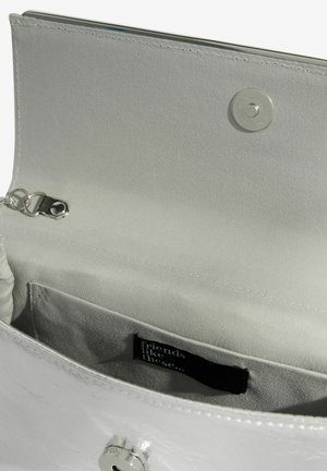 Interiér strieborno-metalickej kabelky s hladkou textíliou vo vnútri. Má malú kapsičku a zapínanie na cvok. Vo vnútri je viditeľná visačka.