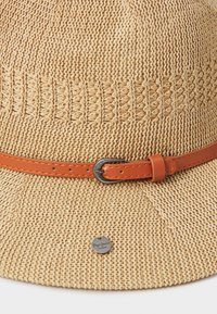 Sombrero de paja tejido en un tono beige claro con un diseño texturizado, que presenta una banda de cuero naranja con una hebilla de plata y un acento metálico con la marca.