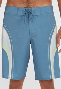 Blaue Boardshorts mit strukturierter Oberfläche. Besitzen ein mehrfarbiges wellenförmiges Design in Grün, Weiß und Hellblau an der Seite. Mit einem Kordelzug am Bund.