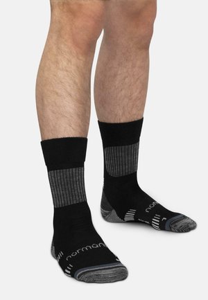Beine mit schwarzen Sportsocken mit grauem verstärktem Fersen- und Zehenbereich, gerippten grauen Einsätzen am oberen Fuß und unteren Wadenbereich.