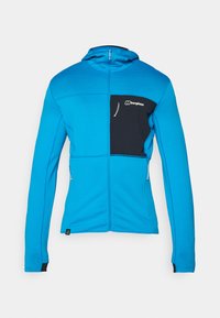 Kék, cipzáras dzseki texturált felülettel, fekete mellzsebbel és két oldalsó zsebbel. Kapucnival és kontrasztos fekete részletekkel rendelkezik.