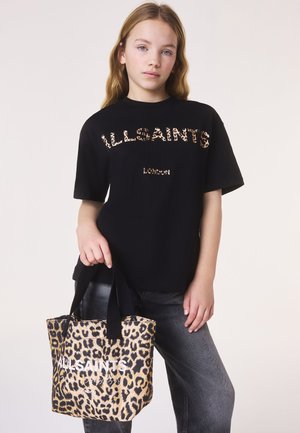 Fiatal személy fekete AllSaints pólót visel, és egy AllSaints logóval és fekete fogantyúval ellátott leopárdmintás vászontáskát tart.