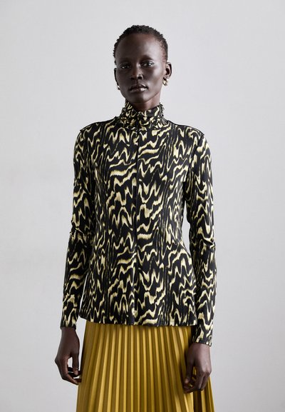Chemise à manches longues ajustée en motif vagues noir et jaune, avec un col haut et une fermeture à boutons, fabriquée en tissu lisse et léger.