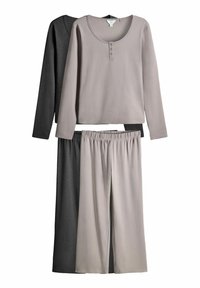 Zwei Langarmoberteile und eine Hose aus grauem und hellbeigem Stoff. Das beige Oberteil hat einen runden Halsausschnitt und eine Detail mit drei Knöpfen.